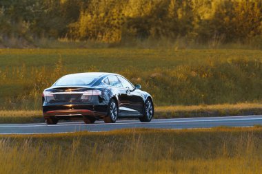 Sakin bir köy yolunda yeni elektrikli otomobil sürüyor