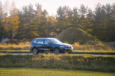 Gün batımında kırsal alanda gezinen arazi aracı.