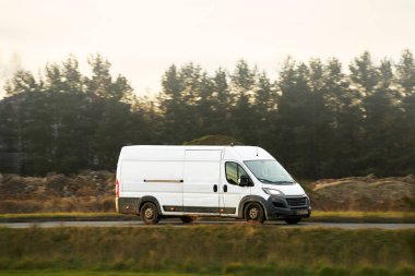 Kırsal yolda giden beyaz kargo minibüsü