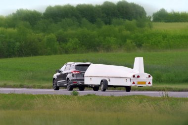 Beyaz planör karavanı kırsal yolda hareket halinde.