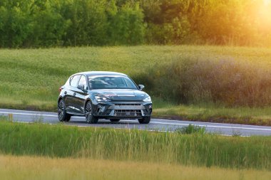 Asfaltlı yolda giden hatchback arabası.