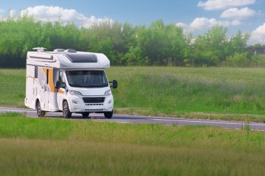 Beyaz karavan güzel yeşil bir arazide seyahat ediyor.