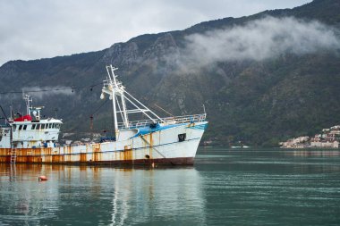 Yeşil dağların yakınında yüzen ticari balıkçı gemisi.