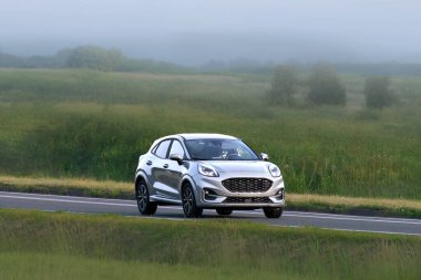 Manzaralı bir yolda giden kompakt elektrikli cip.