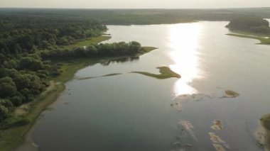 Nehir ve tarlaları olan parlak güneşli bir manzara.
