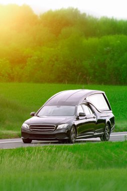 Siyah cenaze arabası tarlaları ve ormanı geçiyor.