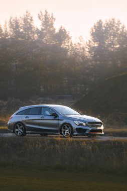 Günbatımında şehir yolunda üst sınıf bir araba.