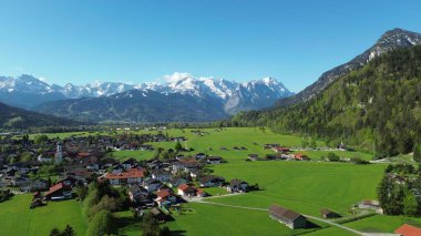 İlkbaharda dramatik bulutlu gökyüzünün altında karla kaplanmış görkemli Bavyera Alpleri