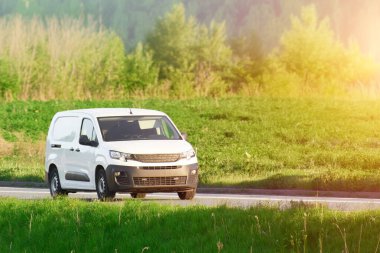 Güneşli bir günde beyaz bir minibüs sürüyordu.