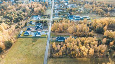 Sonbahar ağaçlarıyla kaplı bir köyün üzerinde sabah sisi