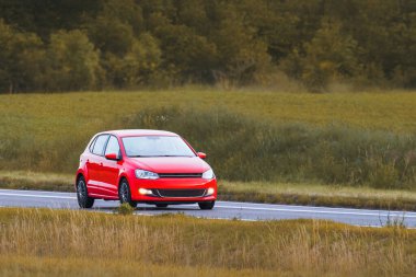 Kırsal kesime park edilmiş üstü açık kırmızı bir araba.