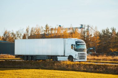 Beyaz kargo kamyonu kırsal yolda gidiyor.