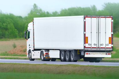 Beyaz kamyon kırsal arazide ilerliyor.