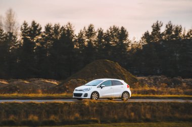 Huzurlu kırsal yolda ilerleyen kompakt araba