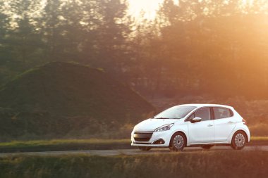 Güneşli köy yolunda araç hareket halinde.