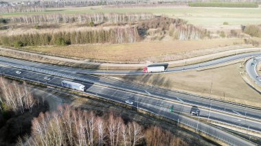 Beyaz ticari kamyon manzaralı bir yolda gidiyor.