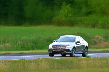 Yeşil bir ormanın yanından geçen aile cipi.