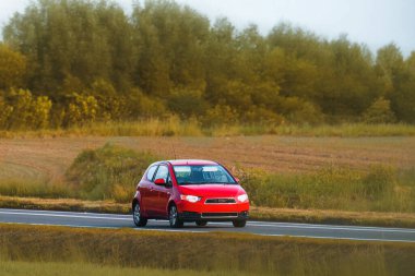 Turbo motorlu hatchback taşra yolunda gidiyor.
