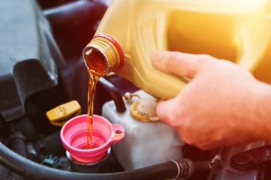 Benzin istasyonunda tamirci el yağı döküyor.