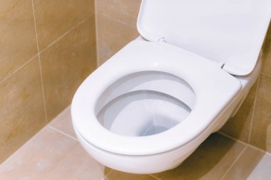 Duvara asılmış tuvalet ve fayansların olduğu minimalist banyo.