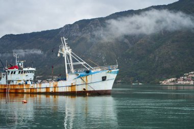 Balıkçı teknesi arka planda dağlarla kenetlenmiş.