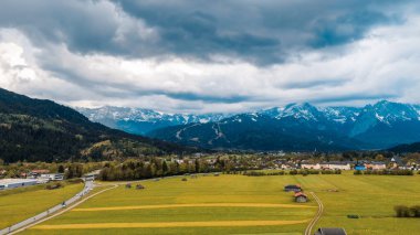 Bulutların altındaki çayırlarda ahşap barakalar.