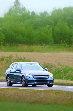 Emlak arabası uzak orman ufkuna doğru gidiyor.