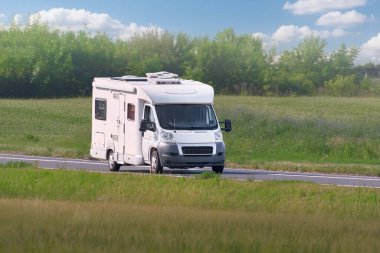 Yazın beyaz bir karavan açık bir otoyolda gidiyor.