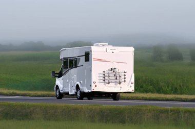 Yazın beyaz bir karavan açık bir otoyolda gidiyor.