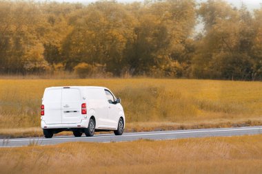 Beyaz kargo kamyonu güzel yeşil bir arazide ilerliyor.