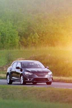 Spor hatchback aracı kırsalda hareket ediyor.