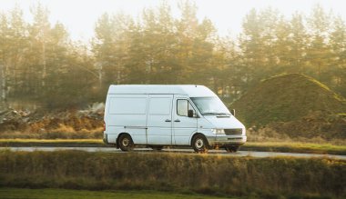 Kırsal yolda giden beyaz kargo minibüsü