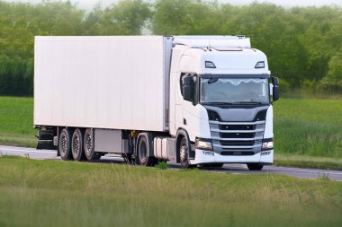 White delivery truck driving on rural highway
