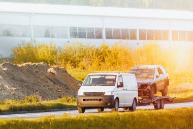 Çekici iki hasarlı arabayı düz karavanda taşıyor.