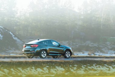 Boş arazinin yanından geçen lüks bir SUV.