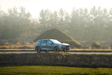 Aile arabası gün batımında kırsal yolda gidiyor.