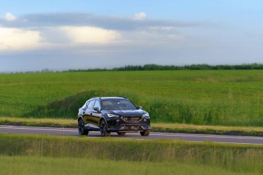 Kırsal bir yolda giden şık beyaz bir araba.