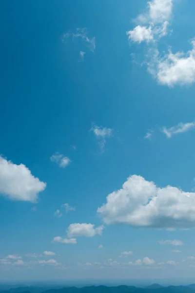 Blue Ridge Mountains of North Carolina, USA looking tiny and distant under striking blue sky with puffy white clouds