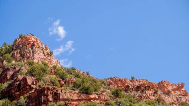 Sedona, Arizona yakınlarında yığılmış kırmızı kayalar ve parlak mavi gökyüzü.