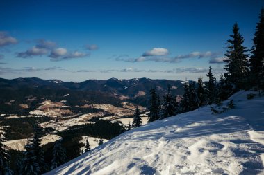 Karla kaplı yamaçta kar kayağı yapan bir adam.