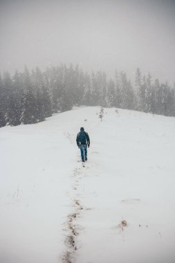 Karla kaplı yamaçta kayak yapan bir adam.