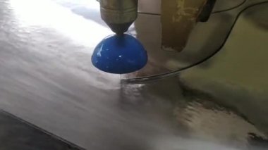  Sayısal yazılımı olan bir makinede su ve kumla ayna kesme