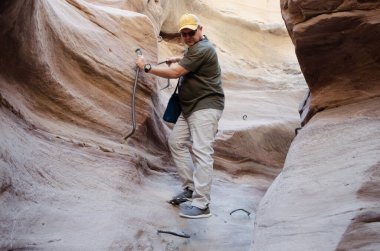 Şişman adam dağlardaki dar bir yarığa iniyor.