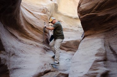 Şişman adam dağlardaki dar bir yarığa iniyor.