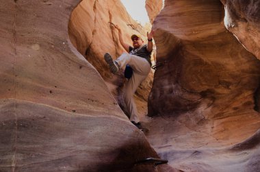 Şişman adam dağlardaki dar bir yarığa iniyor.