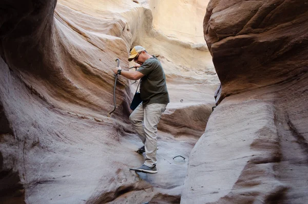 Şişman adam dağlardaki dar bir yarığa iniyor.