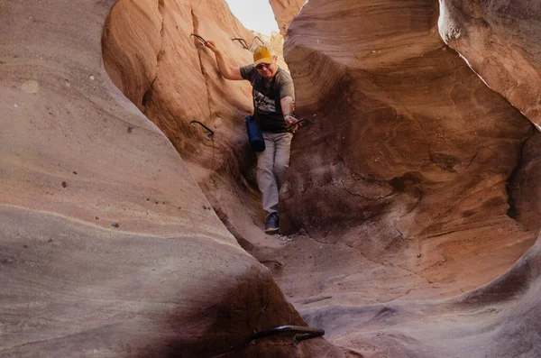 Şişman adam dağlardaki dar bir yarığa iniyor.