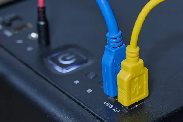 The blue and yellow USB cables are plugged into the ports on the front of the computers system unit — Stock Photo, Image