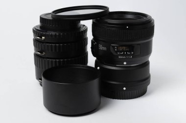 Makro yüzüklü lens ve lens kaputu fotoğrafta dikey konumda ve izole edilmiş.