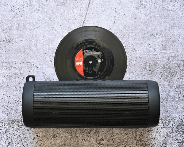 Açık mermerin üzerinde bluetooth hoparlörlü vinil plak var.